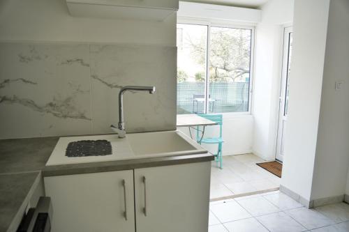 une cuisine blanche avec un évier et une fenêtre dans l'établissement Bas de Villa Vallon des Signes, à La Seyne-sur-Mer