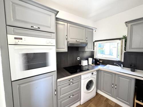 une cuisine avec des armoires blanches et un four à plaques de cuisson dans l'établissement ApartHotel Riviera - LES TOITS D AUGUSTIN - Bright Studio with A C - Old town, à Nice