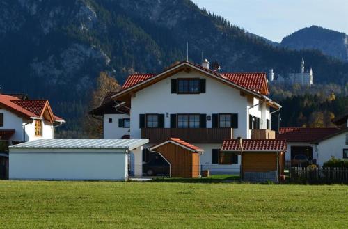 a white house with a garage in a field at Ferienhaus Heidi Ferienwohnung Fernblick in Schwangau