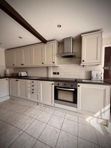 a kitchen with white cabinets and a stove top oven at Churchgate Apartment in Bury Saint Edmunds