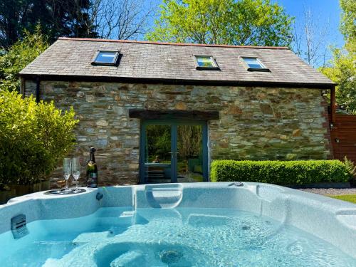 a hot tub in front of a stone house at Sunridge Fishing Lodge with Hot Tub & Giant Cinema in Plymouth