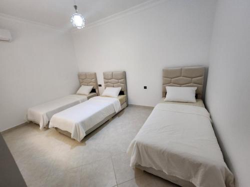 three beds in a room with white walls at Holiday dream of Martil 2 in Martil