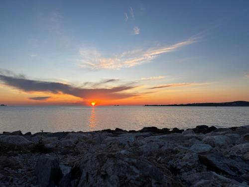 a sunset over a body of water with rocks at Lefteris Home in Parikia