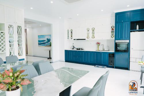 a kitchen with blue cabinets and a table and chairs at Latritcia Boutique Hotel in Cat Ba
