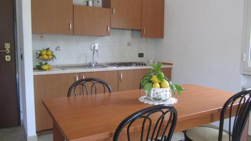 a kitchen with a wooden table with chairs and a bowl of fruit at Agriturismo Turlin in Vallebona