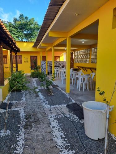 a yellow house with white tables and chairs in it at Vila do Chaves in Itaúnas