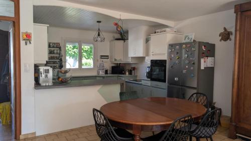 une cuisine avec une table en bois et un réfrigérateur dans l'établissement villa spacieuse avec terrasses et équipements prémium, à Bompas