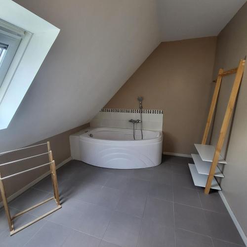 une salle de bain mansardée avec une baignoire dans le grenier dans l'établissement La Maison de Joséphine, à Pleuven