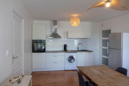 - une cuisine avec des placards blancs, une table et un réfrigérateur dans l'établissement Les suites de Jeanne, à Orléans