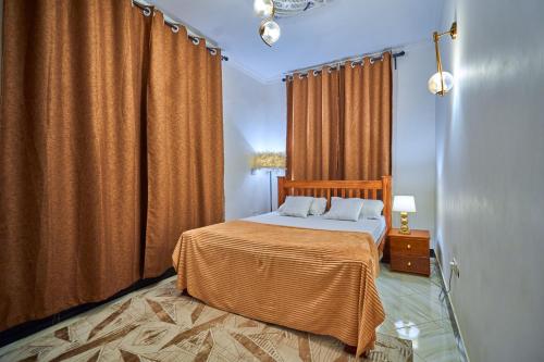 a bedroom with a bed with orange curtains at Favourites home in Arusha