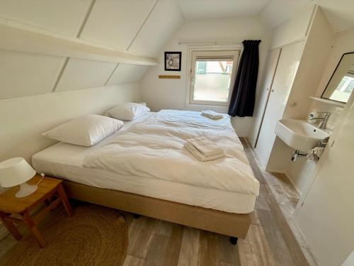 Un dormitorio pequeño con una cama y un lavabo. en Noordwijk Sur-Mer, en Noordwijk aan Zee