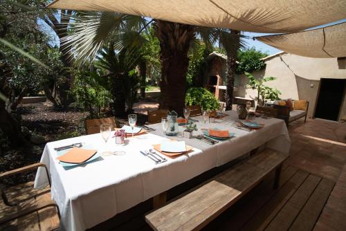 une table avec un tissu de table blanc en haut dans l'établissement Maison jardin tropicale piscine - Quatre Murs Et Un Toit, à Hyères