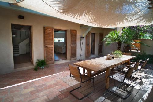 une table et des chaises en bois sur une terrasse dans l'établissement Maison jardin tropicale piscine - Quatre Murs Et Un Toit, à Hyères