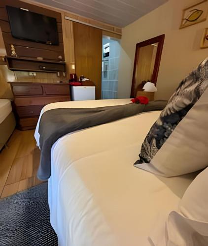 two beds in a hotel room with a flat screen tv at Sua Casa em Noronha - Conforto e Charme na Pousada da Iris in Fernando de Noronha