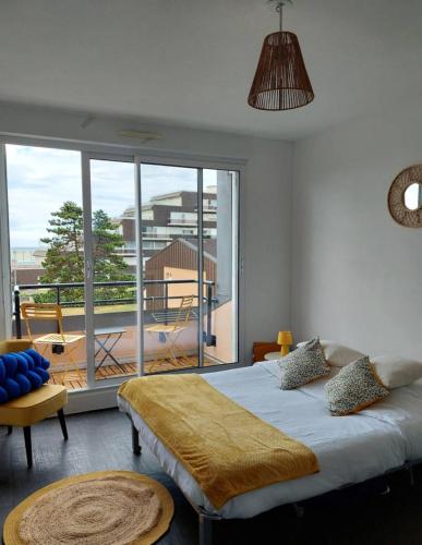 une chambre avec un grand lit et une grande fenêtre dans l'établissement Le Patio, à Courseulles-sur-Mer