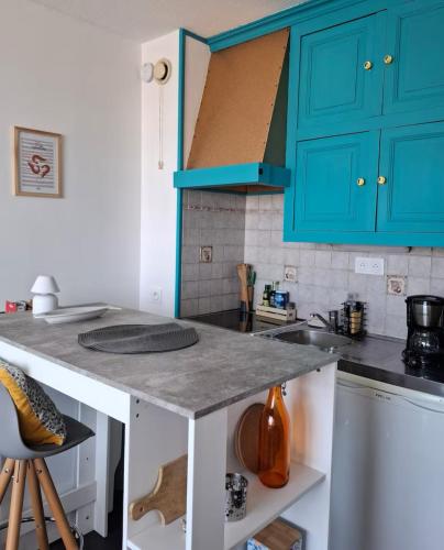 une cuisine avec des armoires bleues et un comptoir dans l'établissement Le Patio, à Courseulles-sur-Mer