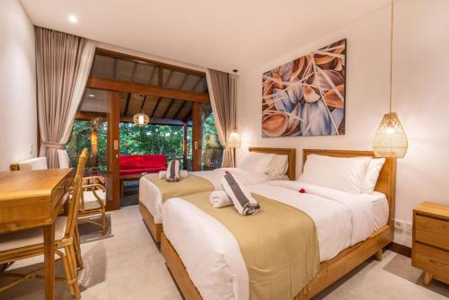 a bedroom with two beds and a table and a desk at Villa Seremi in Bedahulu
