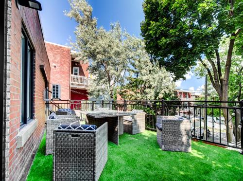 a patio with wicker chairs and tables on the grass at Spacious 4-Bedrooms in HoMa Montreal 22 in Montréal
