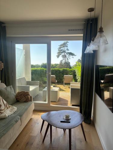un salon avec un canapé et une table dans l'établissement Studio Jardin avec Terrasse VUE MER, à Trouville-sur-Mer