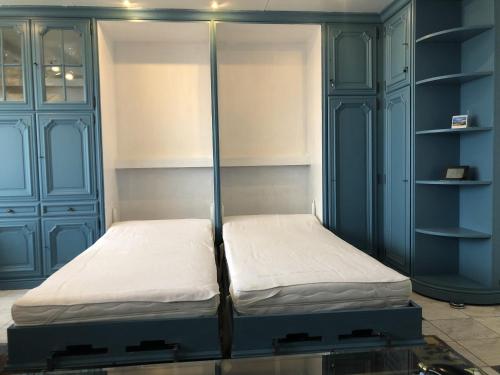 Dos camas en una habitación con armarios y estantes azules. en Wangerooge Haus Monopol - Wohnung Bella Estella, en Wangerooge