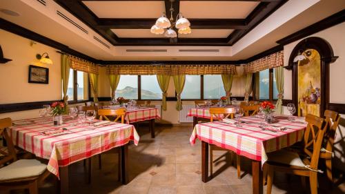 un restaurante con mesas y sillas rojas y blancas en Nobillis - Carpathian Residence en Peştera
