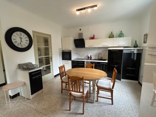 une cuisine avec une table, des chaises et une horloge dans l'établissement Chez Laurette, à Villeneuve-lès-Avignon