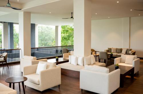 a lobby with white chairs and tables and windows at Waters Edge Hotel in Sri Jayewardenepura Kotte