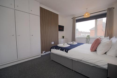a bedroom with a large bed and a large window at Beech Palace - Stylish 3Bed Home with Private Garden, Free Parking & Netflix in Coventry