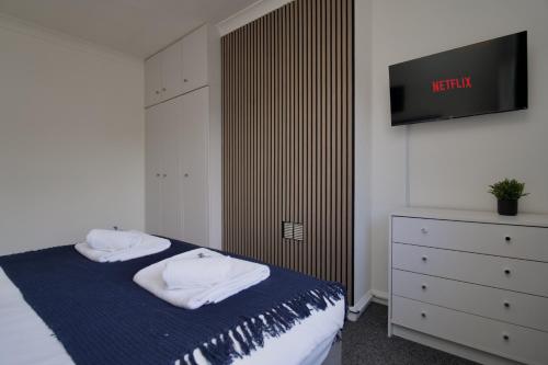 a bedroom with a bed with a tv on the wall at Beech Palace - Stylish 3Bed Home with Private Garden, Free Parking & Netflix in Coventry