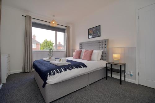 a bedroom with a large bed and a window at Beech Palace - Stylish 3Bed Home with Private Garden, Free Parking & Netflix in Coventry