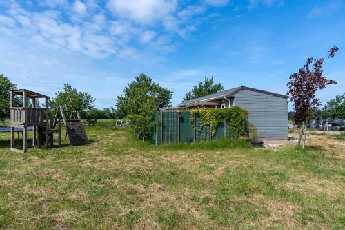 a house and a playground in a field at Hello Zeeland - Hoge duvekotsweg 12 in Oostkapelle