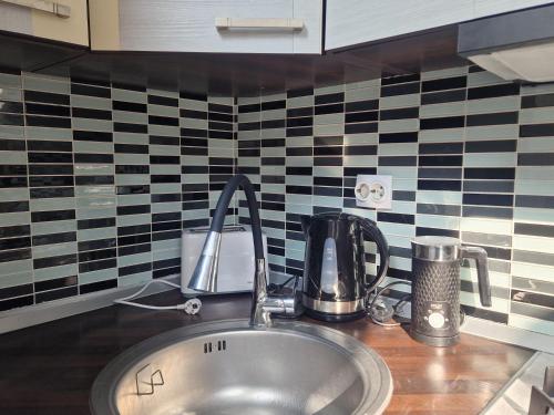 a sink in a kitchen with black and white tiles at Jaukus butas senamiestyje in Klaipėda