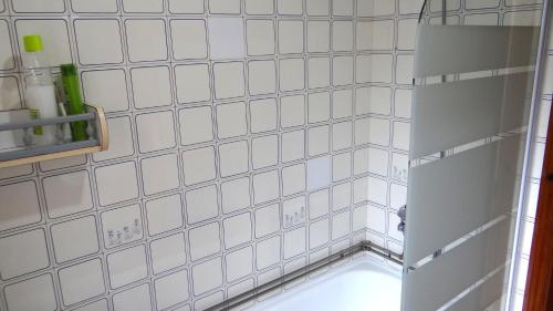 a white tiled bathroom with an open shower door at Casa Ardora - Playa de Carnota in San Mamede de Carnota