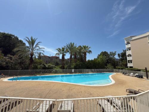 une piscine avec une clôture et des palmiers dans l'établissement Chez Léon, à Hyères