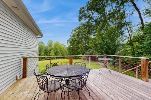 a patio with a table and chairs on a wooden deck at Fly Over Farms in Arden