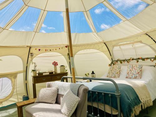 a bedroom in a tent with a bed and a chair at Luxury Stargazing Glamping - Seren Hardd with Hot Tub in Llanidloes