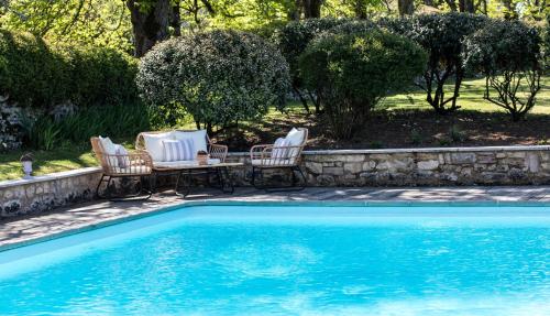- une piscine avec 2 chaises, une table et une table dans l'établissement Les Manibelles, à Amarens