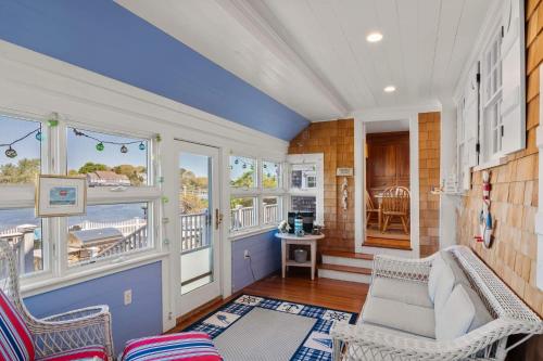 a living room with a couch and chairs and windows at Waterfront Walk to Beach in Barnstable