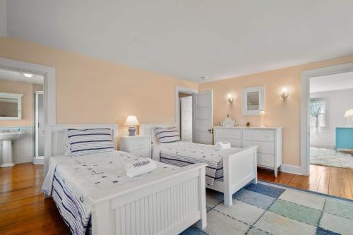 a white bedroom with two beds and a sink at Waterfront Walk to Beach in Barnstable