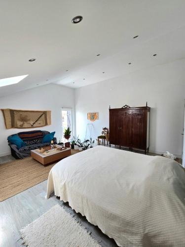 a bedroom with a large white bed and a couch at Bulle Entre Parenthèses in Aroeira