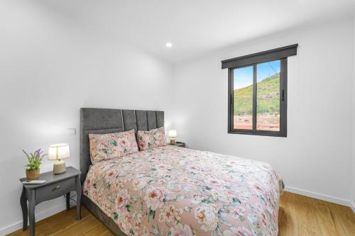 a white bedroom with a bed and a window at Casa da Guida in Machico