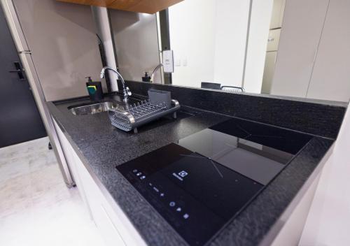 a kitchen counter with a sink and a laptop on it at Urbà Home Stay by Housi in Goiânia