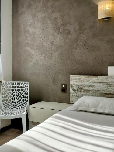 a bedroom with a white bed and a chair at Hôtel La Tour des Anglais in Mayenne