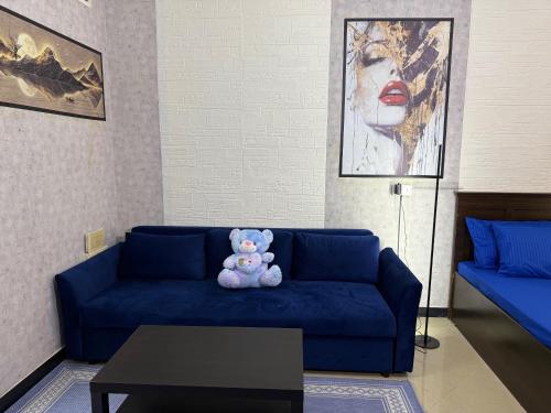 a teddy bear sitting on a blue couch in a living room at Large Studio Apartment for 4 in Sharjah