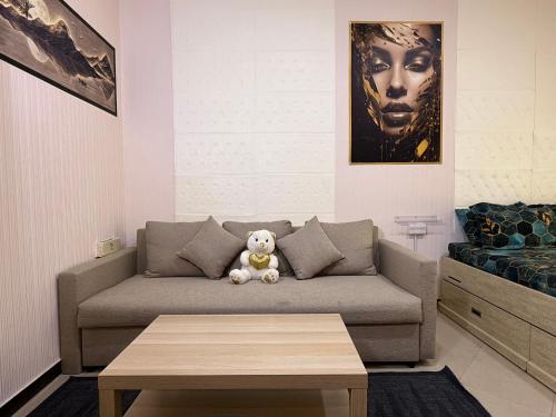 a living room with a couch with a teddy bear at Large Studio Apartment for 4 in Sharjah