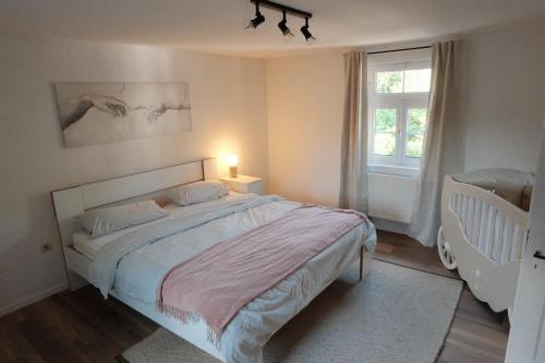 een witte slaapkamer met een bed en een raam bij Ferienhaus Fachwerklust in der Eifel in Mechernich