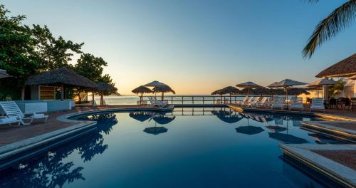 a swimming pool with chairs and umbrellas on the beach at Park Royal Beach Huatulco - All Inclusive in Santa Cruz Huatulco
