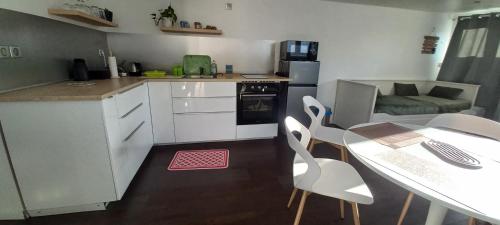 une cuisine avec des armoires blanches et une table et des chaises dans l'établissement Charmant t2 plein pied, à La Celle-sous-Gouzon