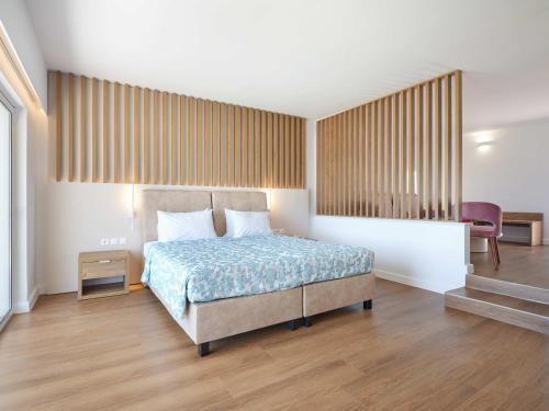 a bedroom with a bed and a table and a chair at Kinetta Beach Resort and Spa in Kineta