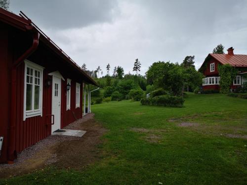 a red building with a yard next to a house at Nybyggd stuga i naturskönt läge in Sunne
